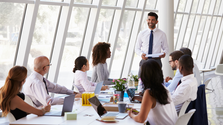 manager speaking to employees at table